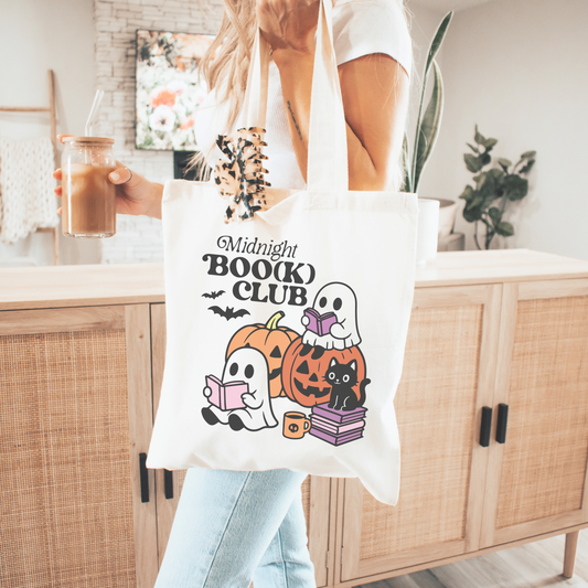 Person holding a tote bag with 'Midnight Book Club' design.